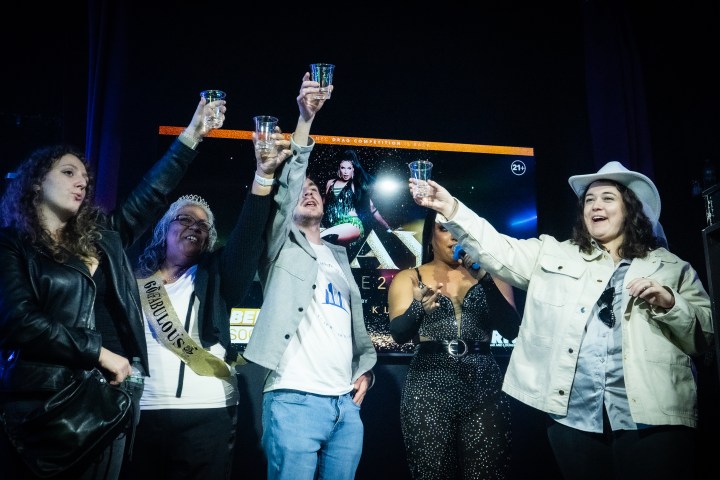 Group of people raising glasses in a celebratory toast on stage.
