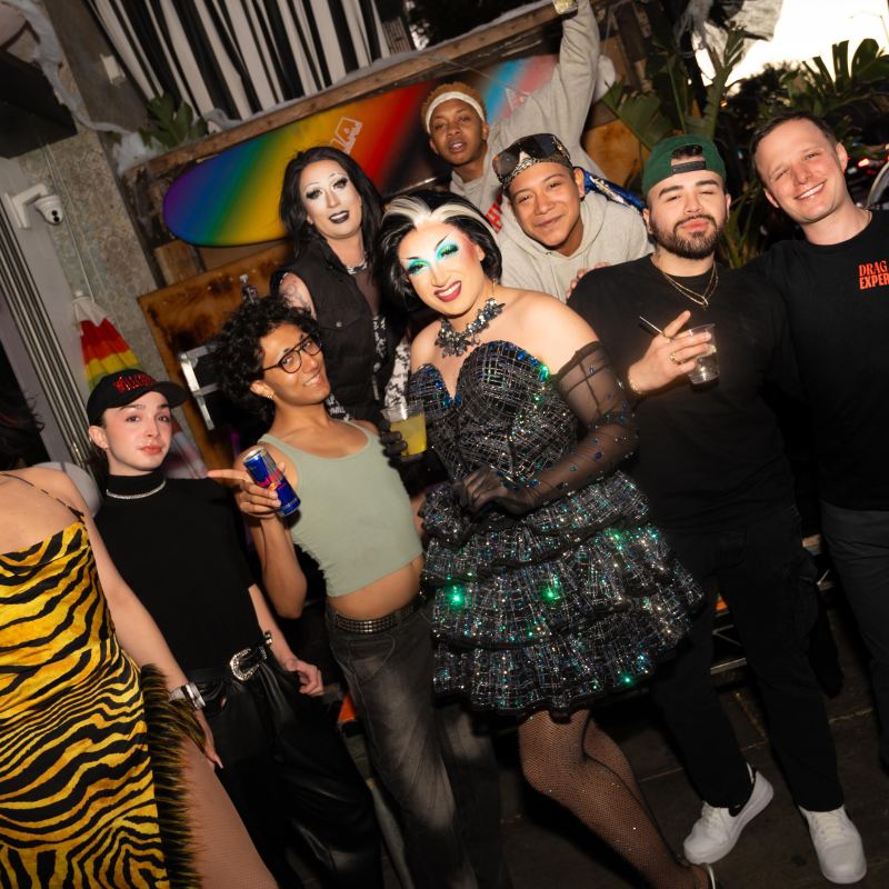 Group of people in colorful, festive outfits posing together at a lively indoor event.