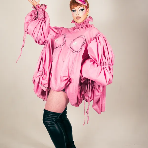 Person in pink outfit with puffy sleeves and hat, wearing black thigh-high boots in a pose.